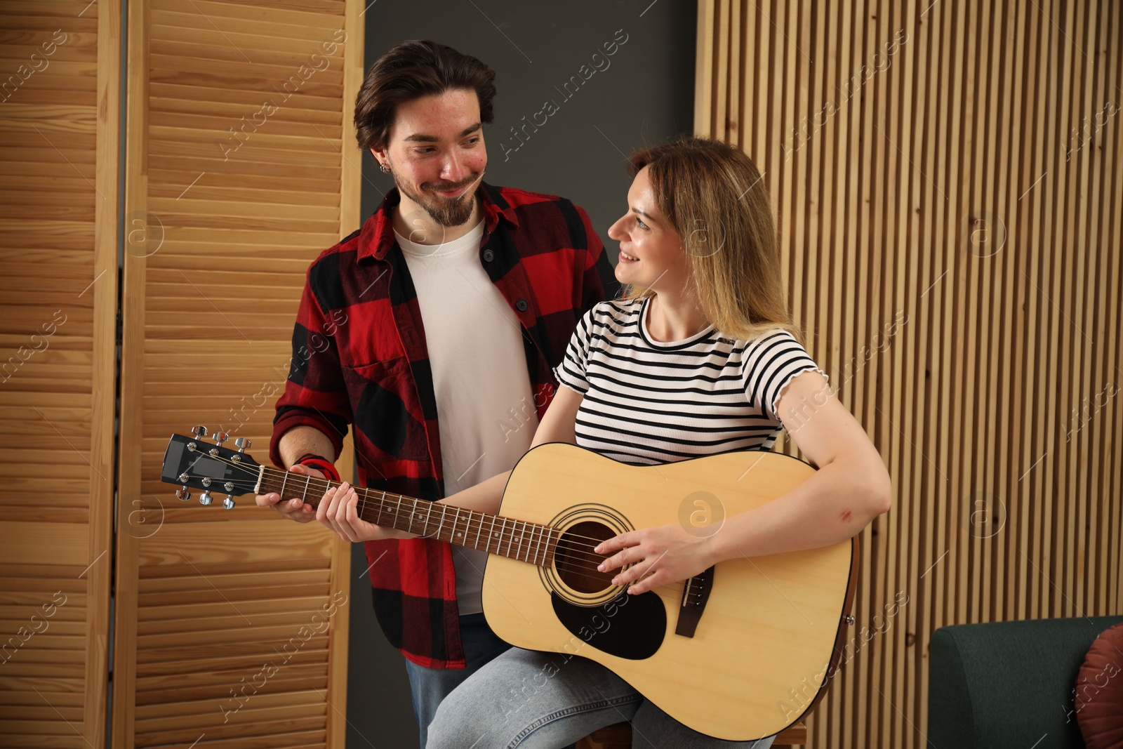 Photo of Tutor teaching woman to play guitar indoors