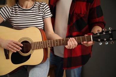 Photo of Tutor teaching woman to play guitar at home, closeup