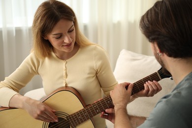 Photo of Tutor teaching woman to play guitar at home