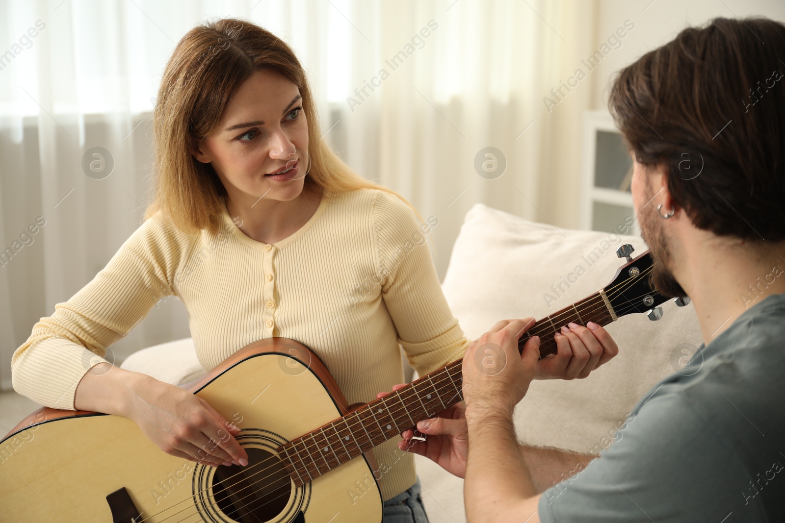 Tutor teaching woman to play guitar at home Photo of Tutor teaching woman to play guitar at home
