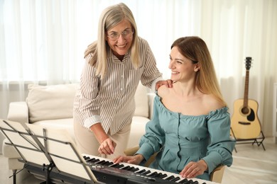 Photo of Tutor teaching woman to play piano indoors