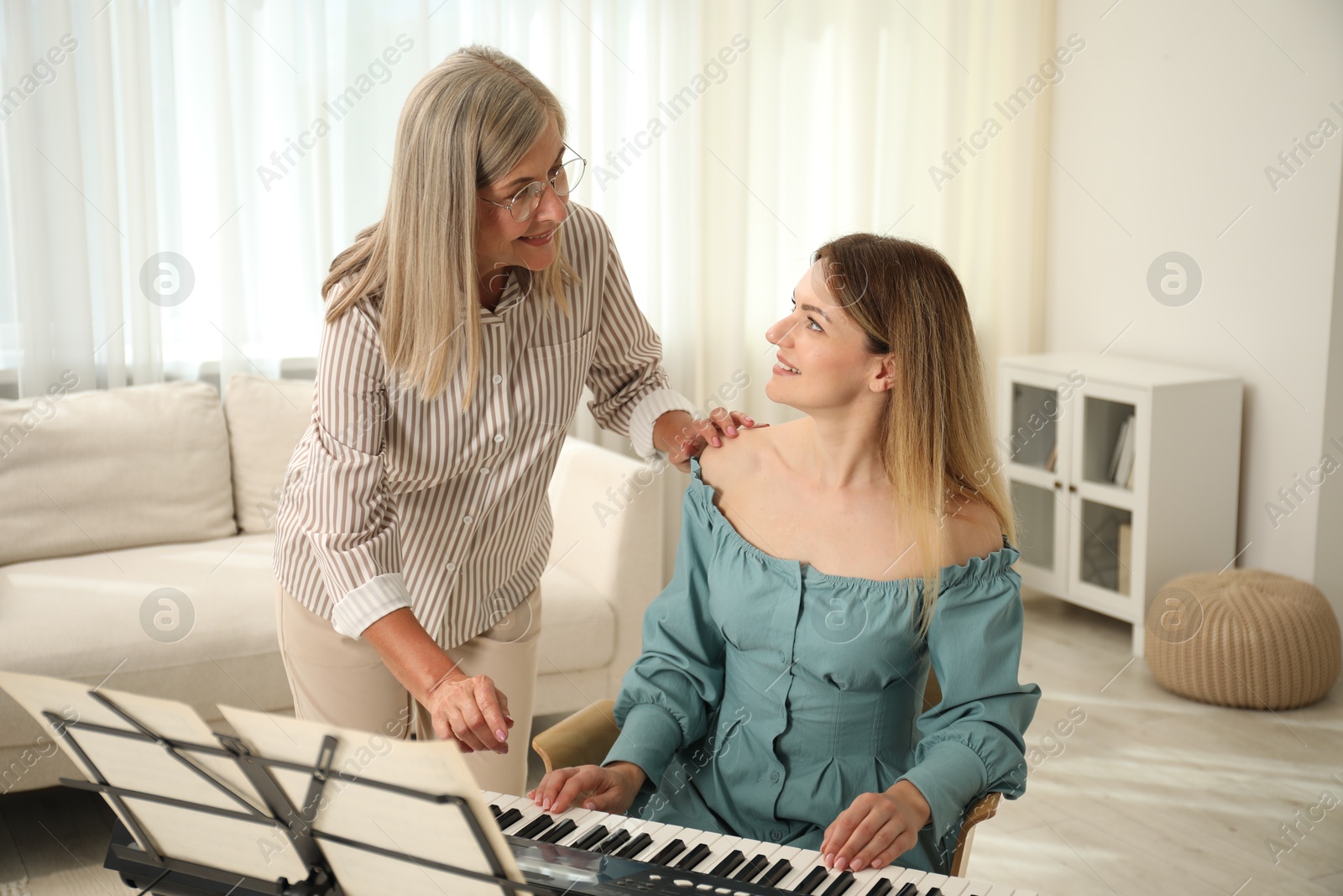 Photo of Tutor teaching woman to play piano indoors