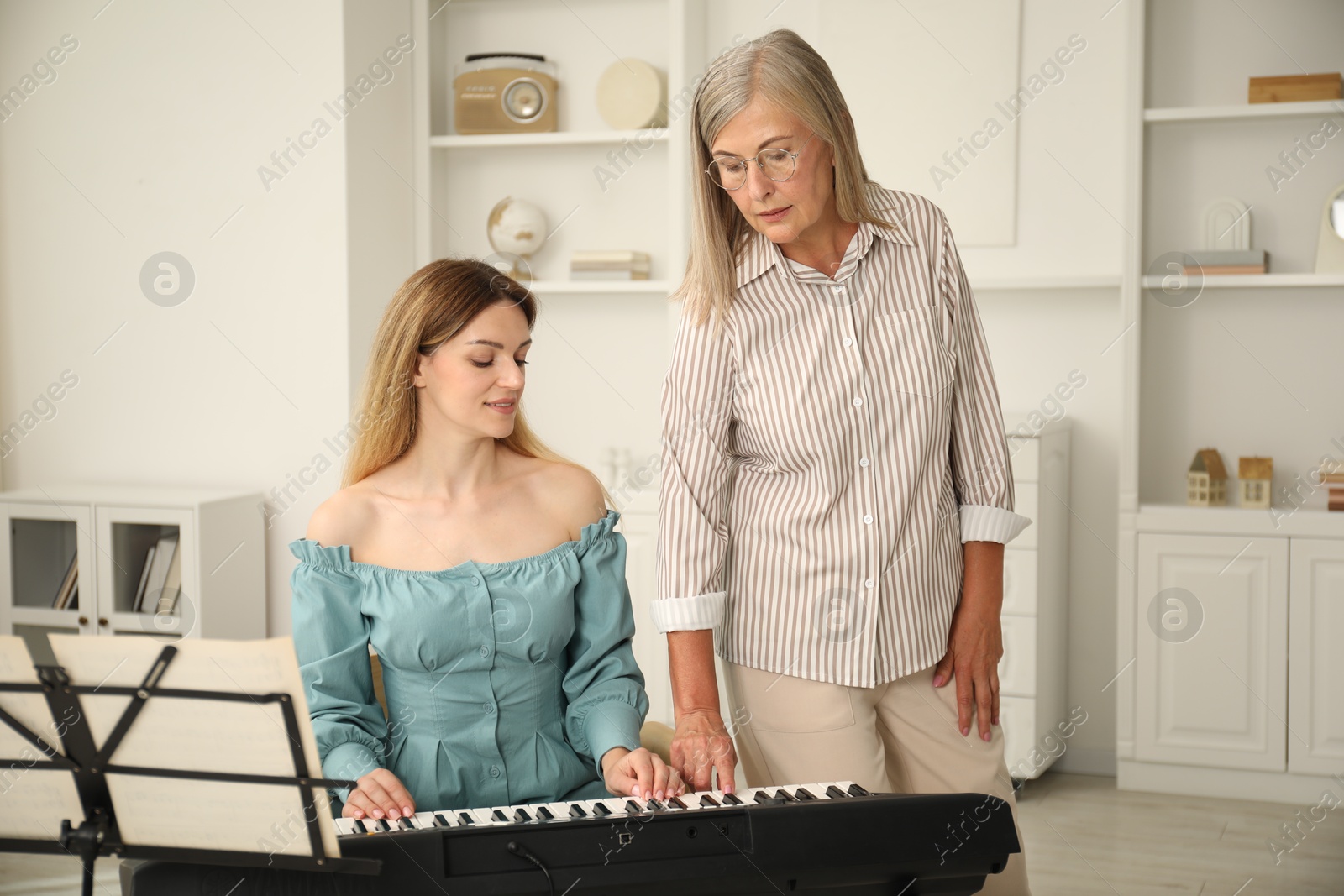 Photo of Tutor teaching woman to play piano indoors