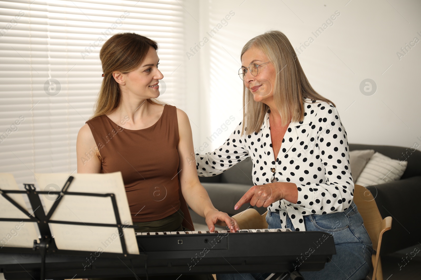 Photo of Tutor teaching woman to play piano indoors