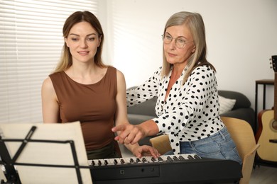 Photo of Tutor teaching woman to play piano indoors