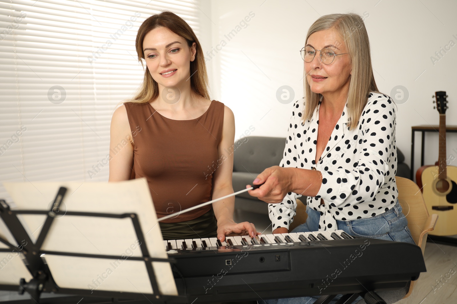 Tutor teaching woman to play piano indoors Photo of Tutor teaching woman to play piano indoors