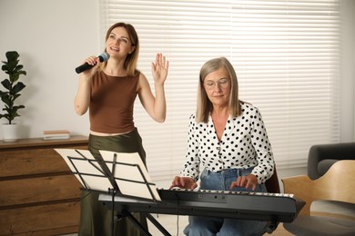 Photo of Woman learning to sing while her teacher accompanying on piano indoors