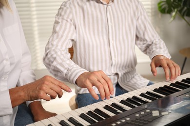 Photo of Tutor teaching man to play piano indoors, closeup