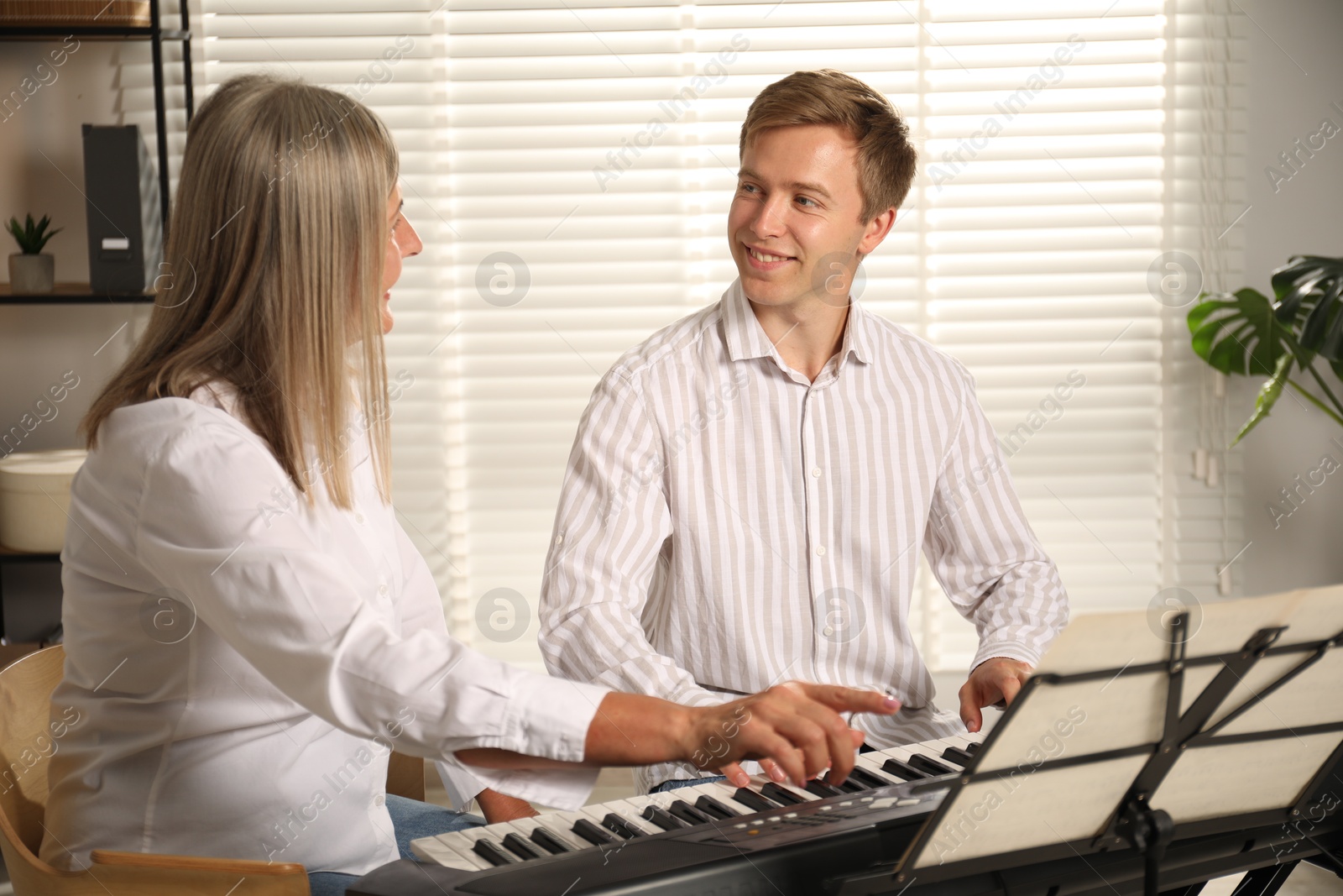 Photo of Tutor teaching man to play piano indoors