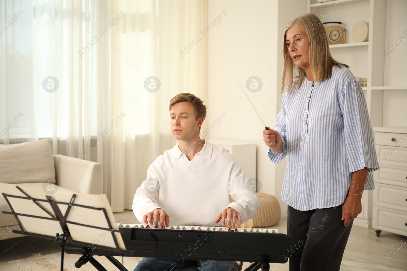 Photo of Tutor teaching man to play piano indoors