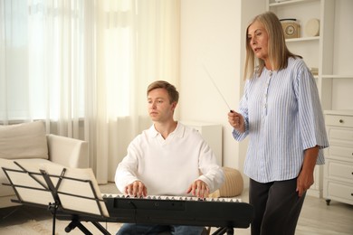 Photo of Tutor teaching man to play piano indoors