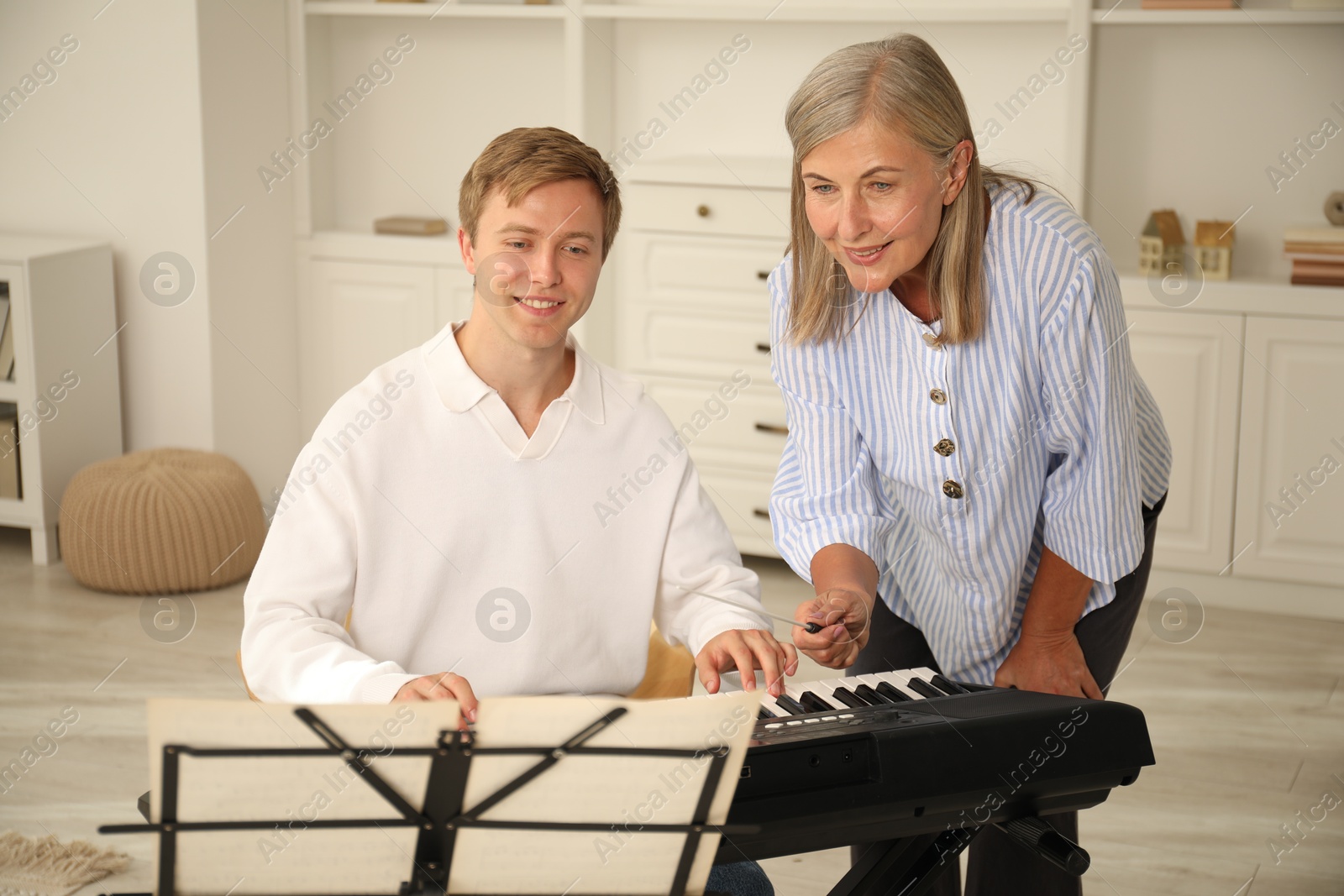Photo of Tutor teaching man to play piano indoors