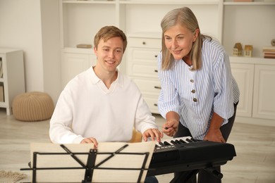 Photo of Tutor teaching man to play piano indoors