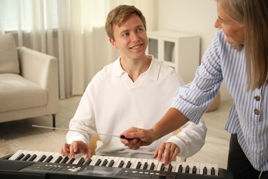 Photo of Tutor teaching man to play piano indoors