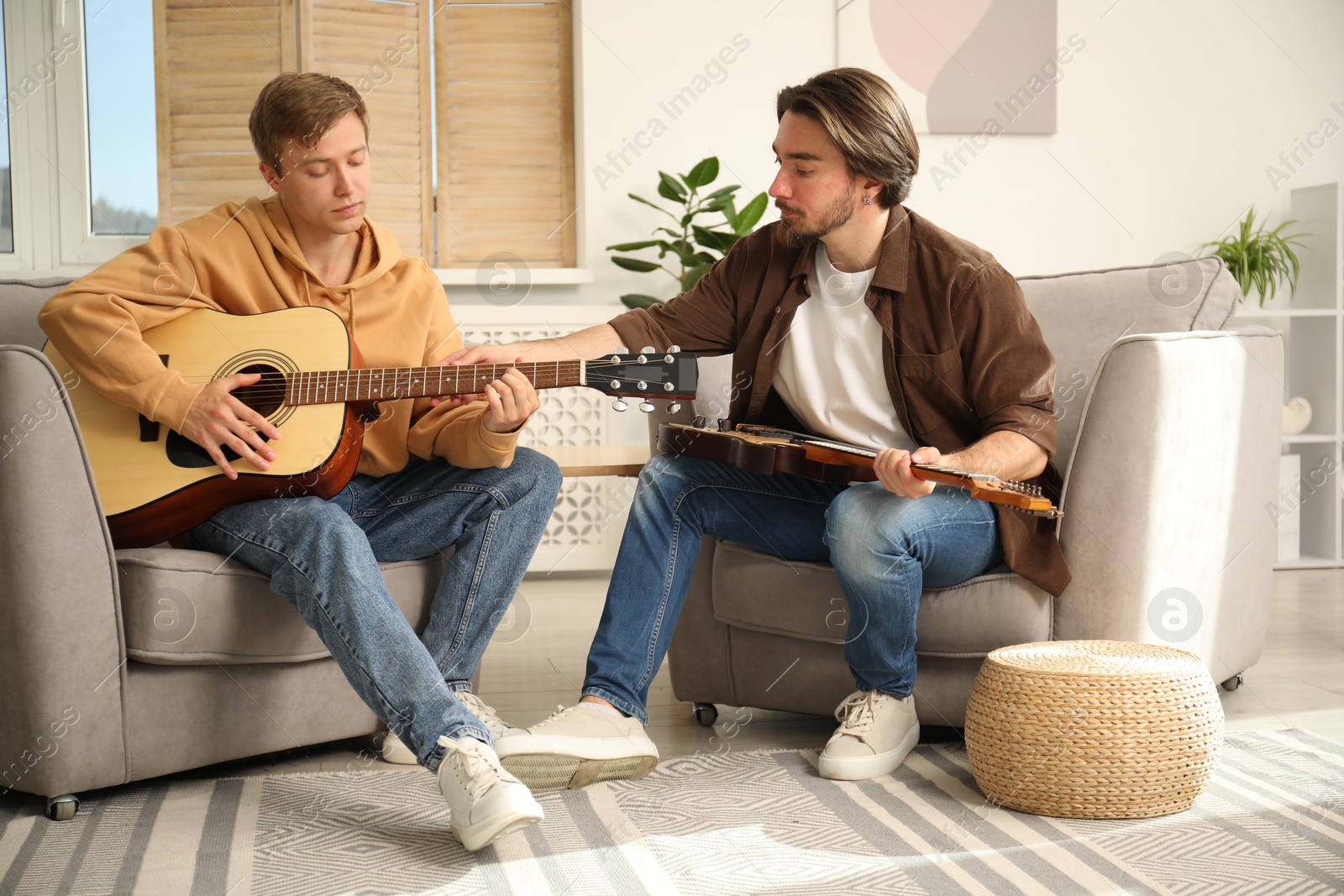 Photo of Tutor teaching man to play guitar at home
