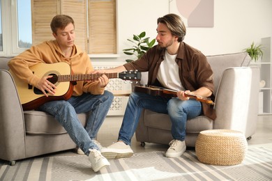 Photo of Tutor teaching man to play guitar at home