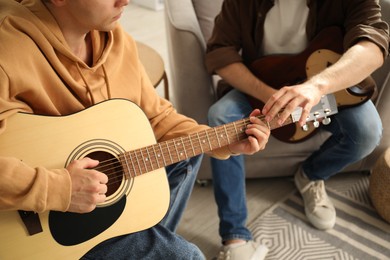 Photo of Tutor teaching man to play guitar at home, closeup