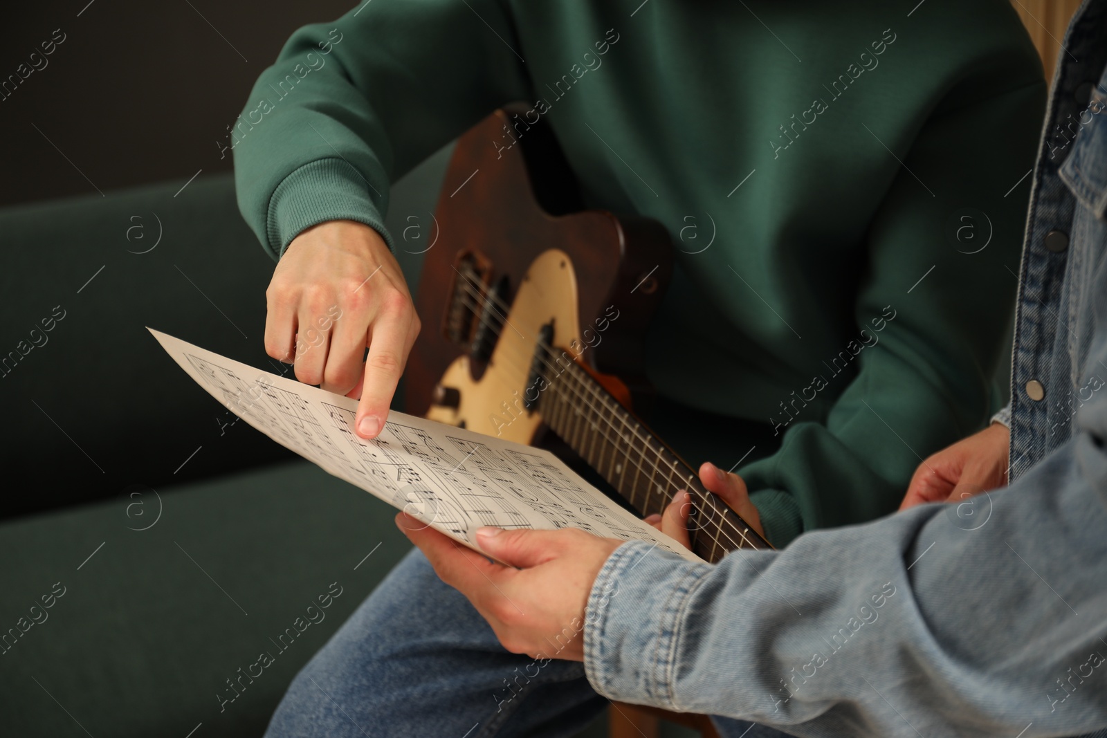 Photo of Tutor teaching man to play guitar at home, closeup