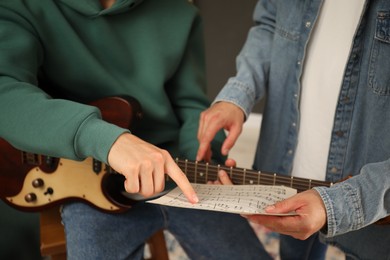 Photo of Tutor teaching man to play guitar at home, closeup