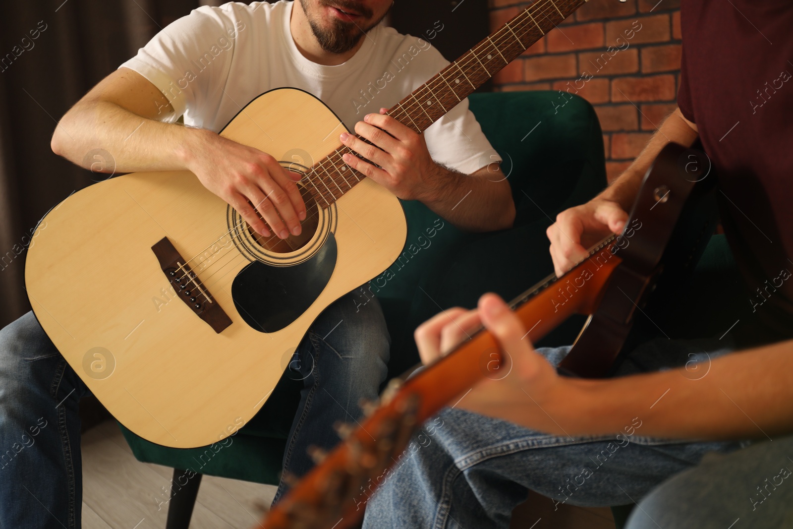 Photo of Tutor teaching man to play guitar at home, closeup