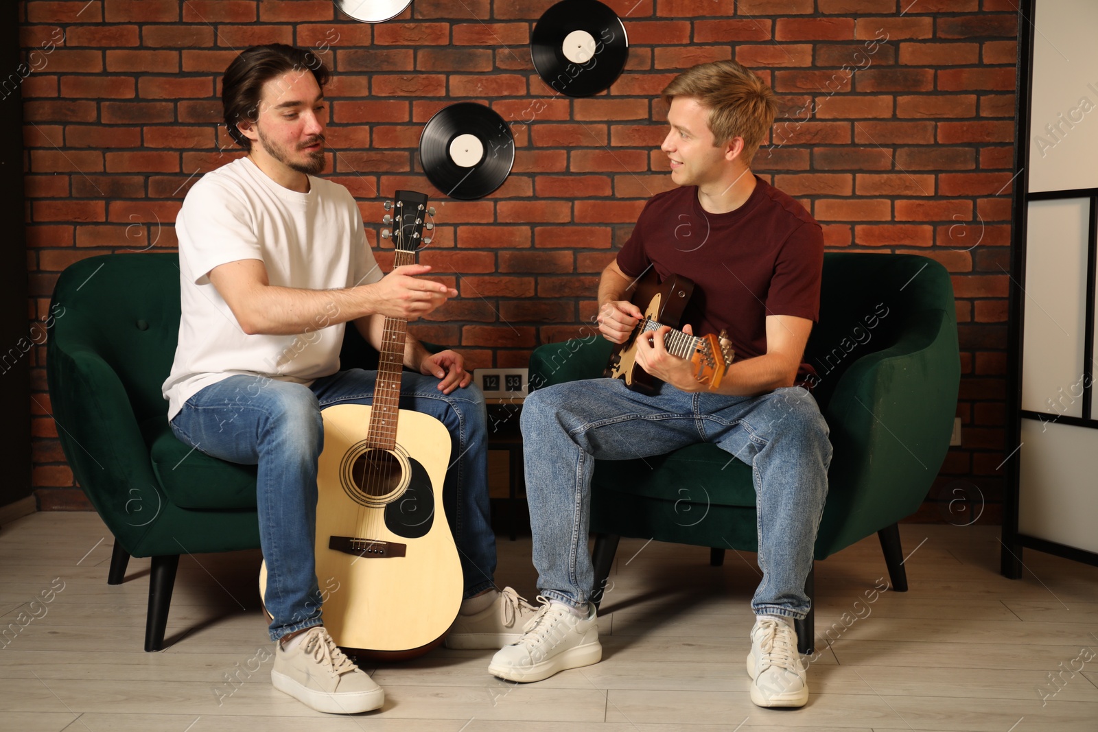 Photo of Tutor teaching man to play guitar indoors