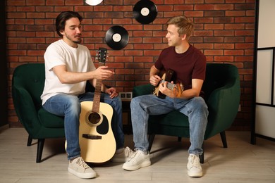 Photo of Tutor teaching man to play guitar indoors