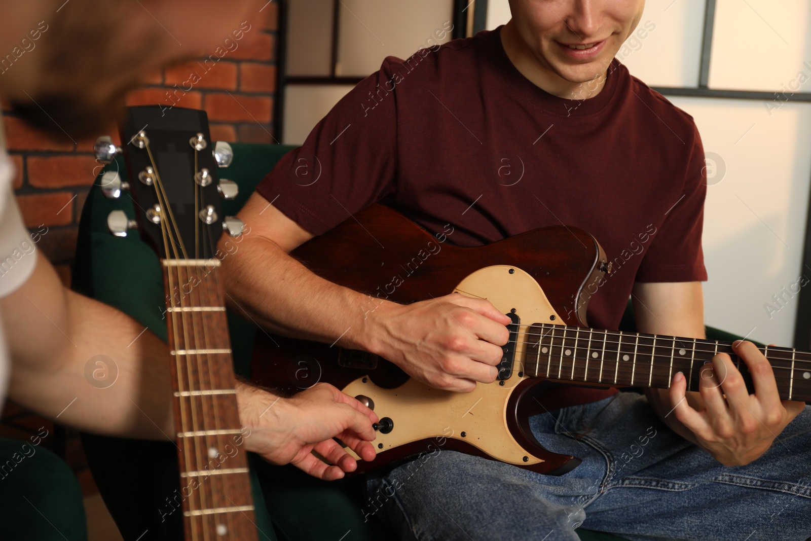 Photo of Tutor teaching man to play guitar at home, closeup
