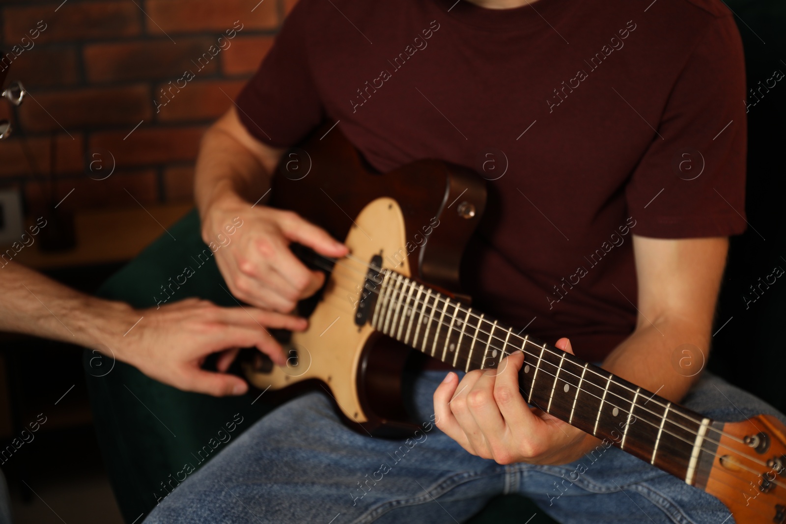 Photo of Tutor teaching man to play guitar at home, closeup