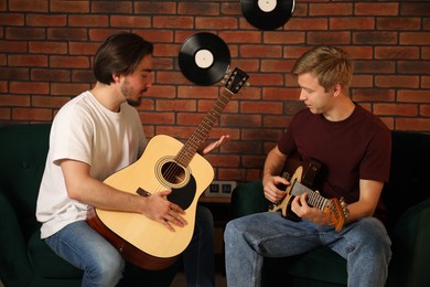 Photo of Tutor teaching man to play guitar indoors