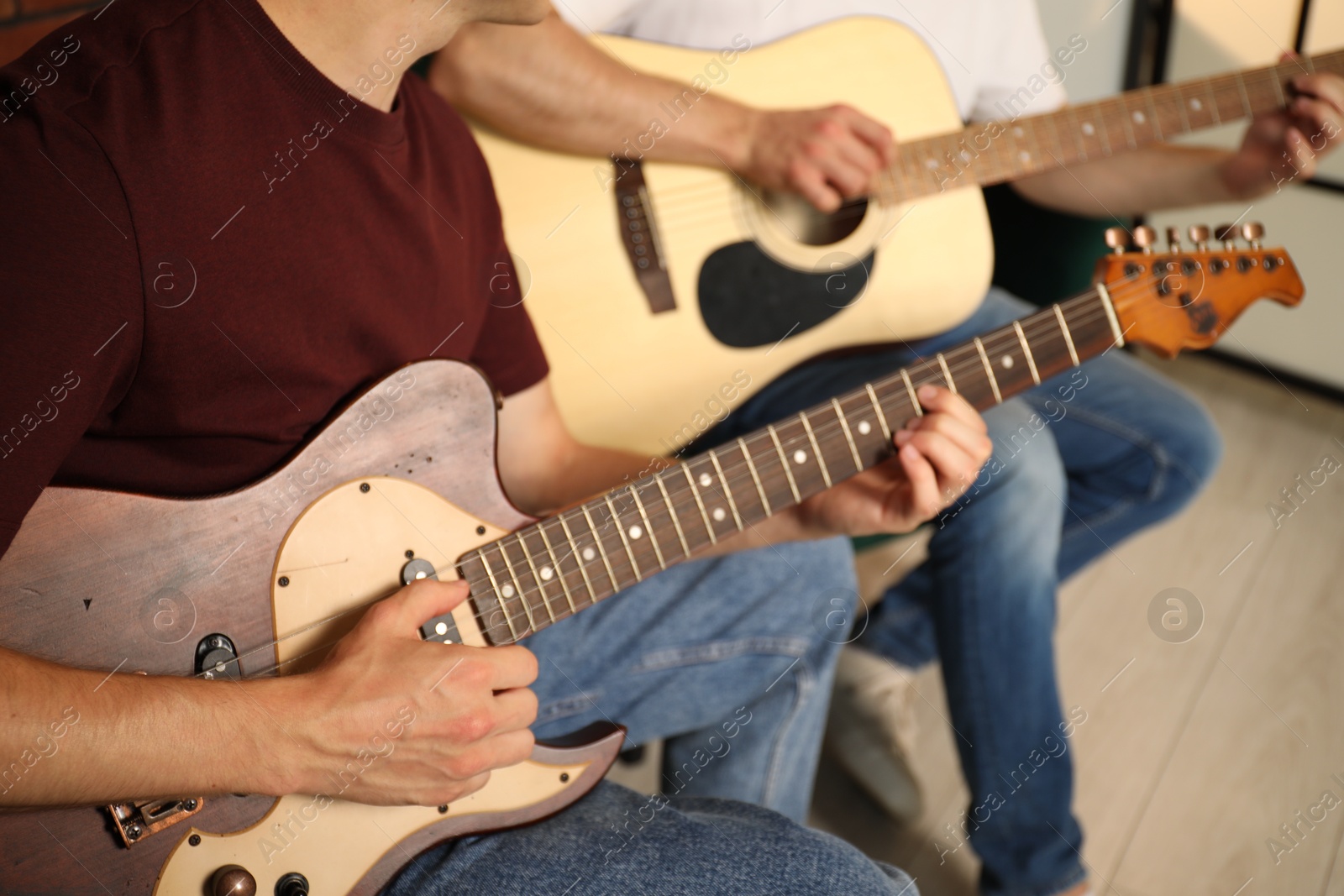 Photo of Tutor teaching man to play guitar at home, closeup