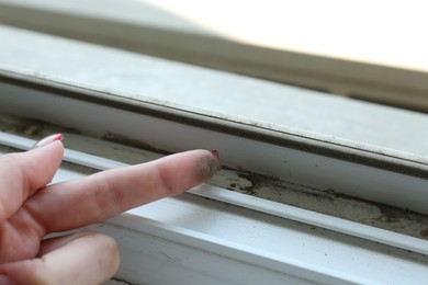 Photo of Woman showing dust from window frame indoors, closeup