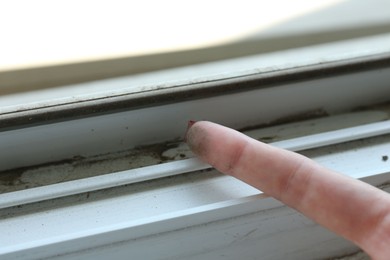 Photo of Woman showing dust from window frame indoors, closeup
