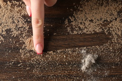 Photo of Woman swiping dust from wooden table, top view