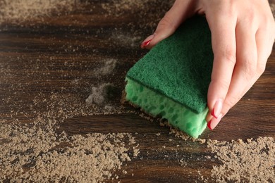 Photo of Woman wiping dust off wooden table, closeup