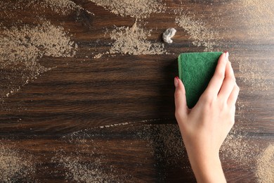 Photo of Woman wiping dust off wooden table, top view. Space for text
