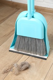 Photo of Dust bunny, dustpan and broom on floor indoors