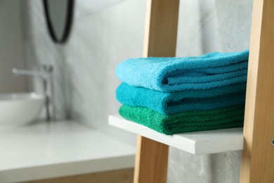 Photo of Fresh colorful terry towels on shelf in bathroom, closeup. Space for text