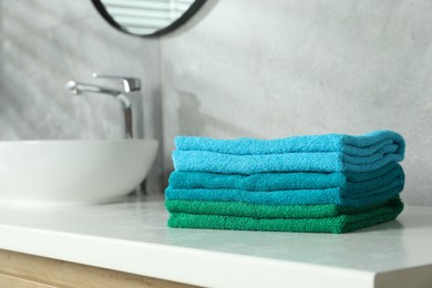 Photo of Fresh colorful terry towels on counter in bathroom. Space for text