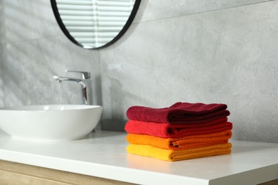 Photo of Fresh colorful terry towels on counter in bathroom. Space for text