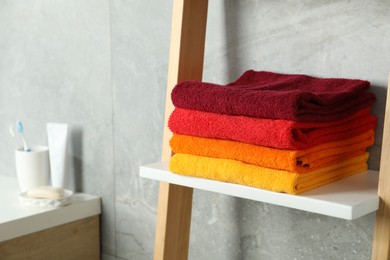 Photo of Fresh colorful terry towels on shelf in bathroom, closeup. Space for text
