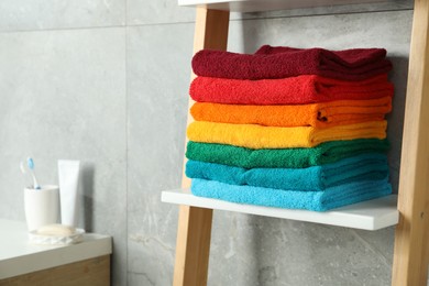 Photo of Fresh colorful terry towels on shelf in bathroom, closeup. Space for text