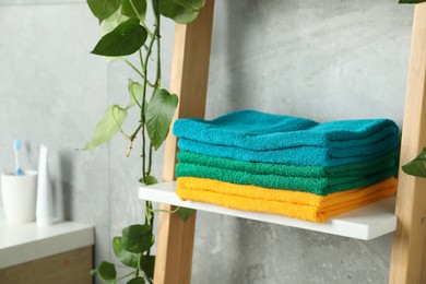 Photo of Fresh colorful terry towels on shelf in bathroom, closeup