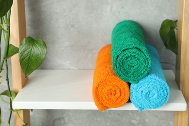 Photo of Fresh colorful terry towels on shelf in bathroom, closeup. Space for text