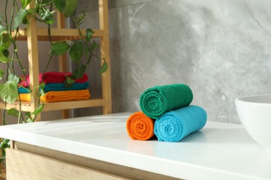 Photo of Fresh colorful terry towels on counter in bathroom. Space for text