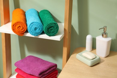 Photo of Fresh colorful terry towels and hygiene products in bathroom