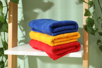 Photo of Fresh colorful terry towels on shelf in bathroom, closeup