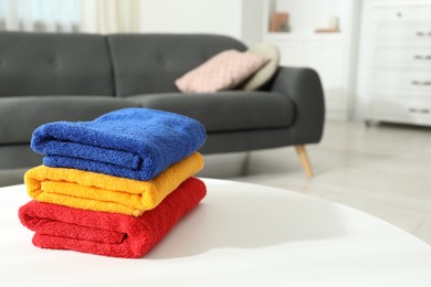 Photo of Fresh colorful terry towels on white table at home, closeup. Space for text