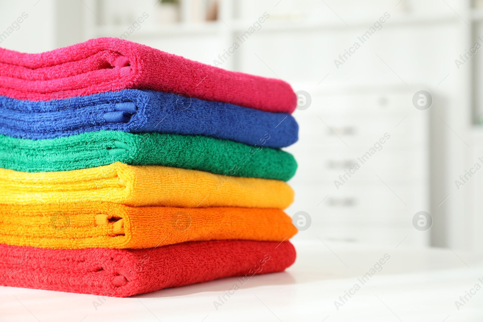 Photo of Fresh colorful terry towels on white table at home, closeup. Space for text
