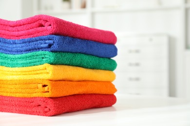 Photo of Fresh colorful terry towels on white table at home, closeup. Space for text