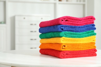 Photo of Fresh colorful terry towels on white table at home, closeup. Space for text